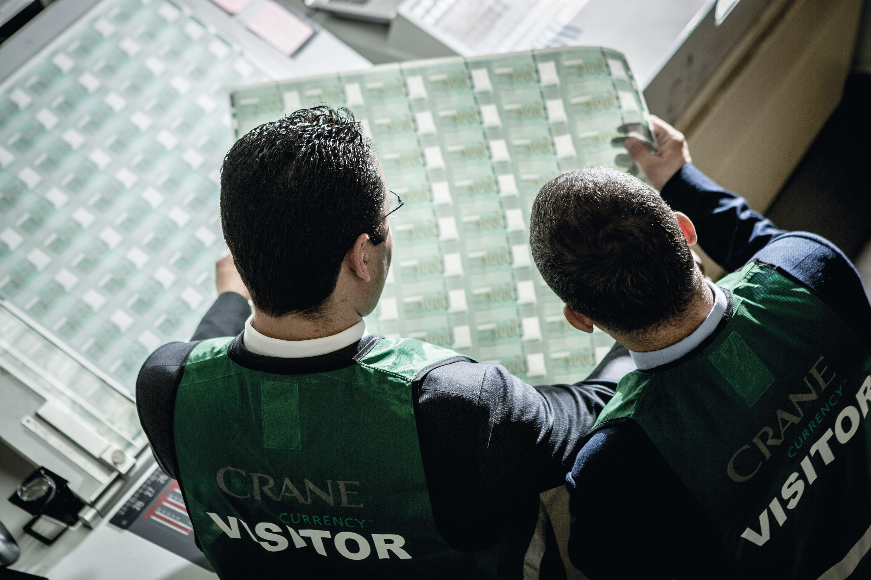 Two central bankers inspecting a product sheet.