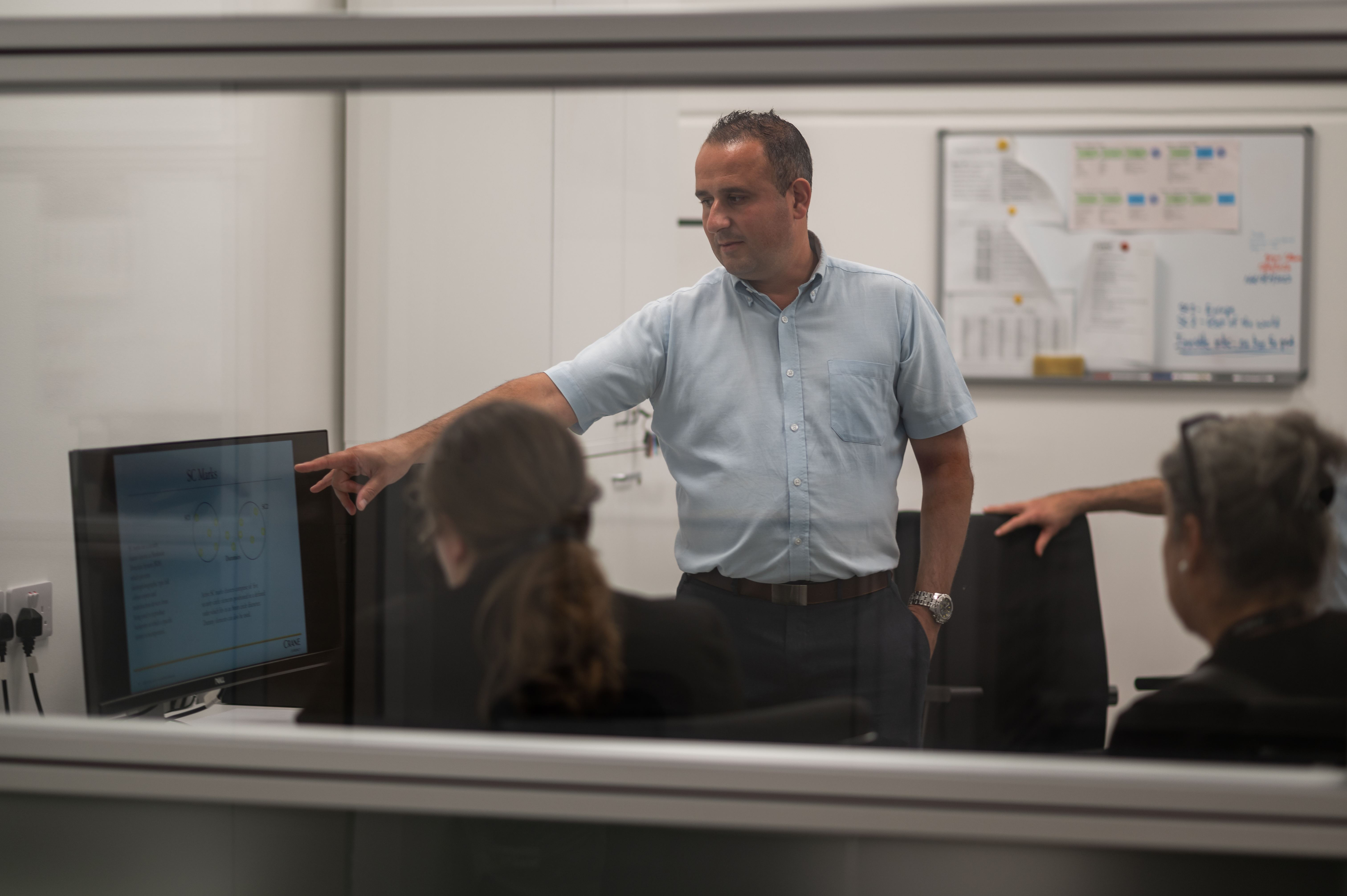 Stefan Fenech showing his team of designers something on a computer screen.